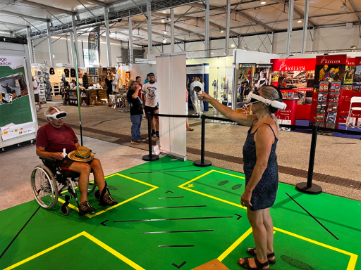 Inklusion Eine Person im Rollstuhl und eine Frau spielen ein VR-Spiel