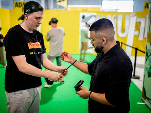 Zeigt eure Hände! Ein Operator hilft einem Nutzenden, die VR-Controller anzuziehen